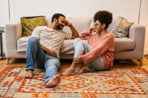 Cheerful couple talking while sitting on floor at home